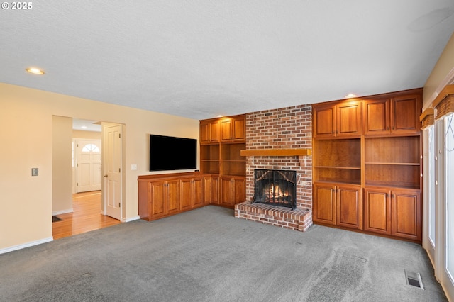 unfurnished living room featuring built in shelves, light colored carpet, and a brick fireplace