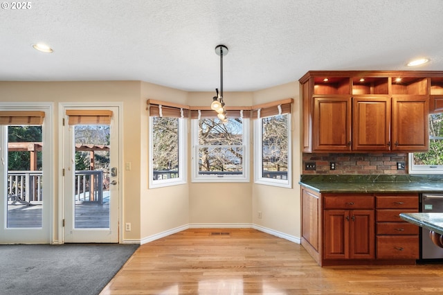 kitchen with stainless steel dishwasher, decorative light fixtures, light wood-type flooring, a textured ceiling, and decorative backsplash