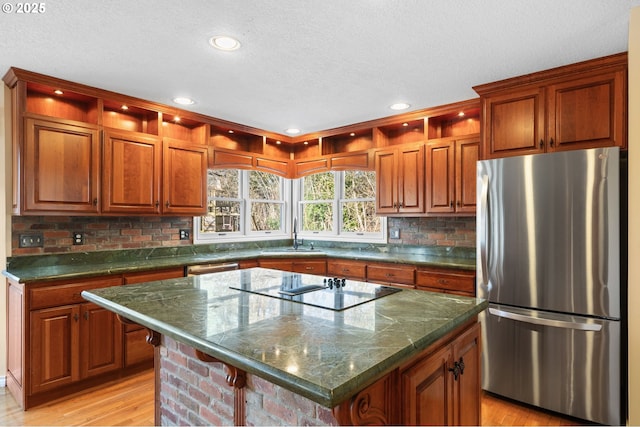 kitchen with a kitchen island, a kitchen bar, sink, stainless steel refrigerator, and light wood-type flooring