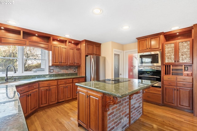 kitchen featuring light hardwood / wood-style flooring, appliances with stainless steel finishes, sink, a center island, and a breakfast bar area