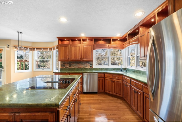 kitchen featuring sink, decorative light fixtures, a healthy amount of sunlight, a kitchen island, and stainless steel appliances