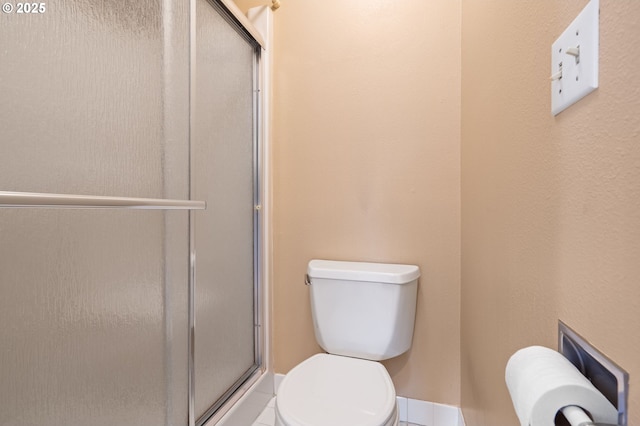 bathroom with toilet, tile patterned floors, and a shower with shower door