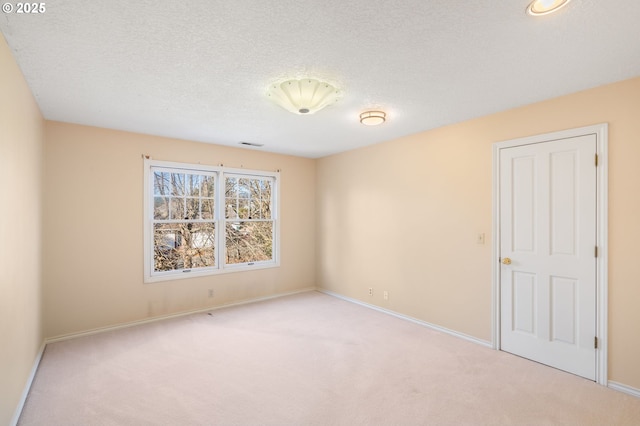 spare room featuring light colored carpet and a textured ceiling