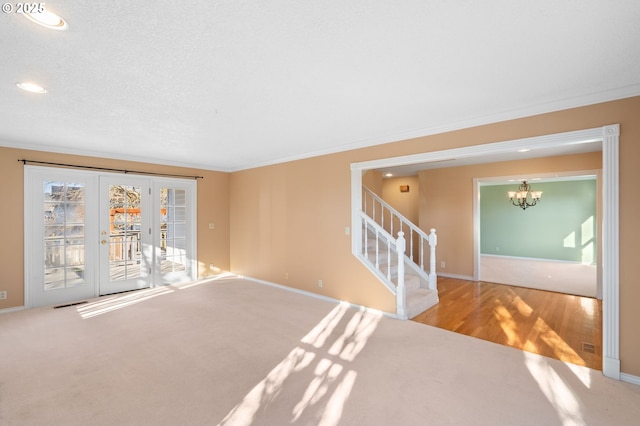 carpeted spare room with a textured ceiling, a chandelier, and ornamental molding