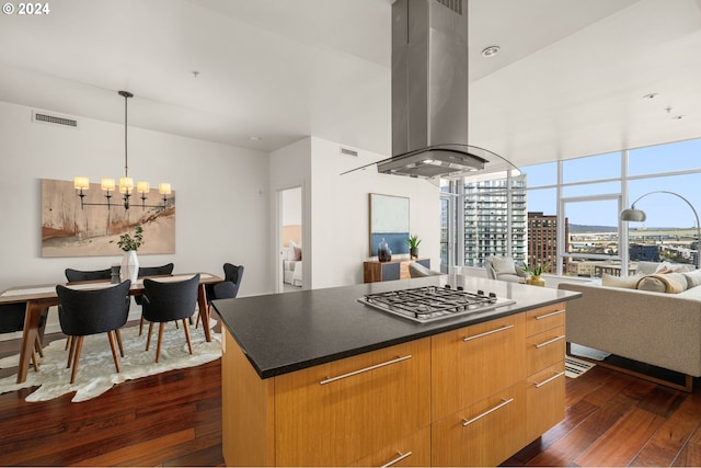 kitchen featuring hanging light fixtures, stainless steel gas cooktop, island exhaust hood, a center island, and dark hardwood / wood-style flooring