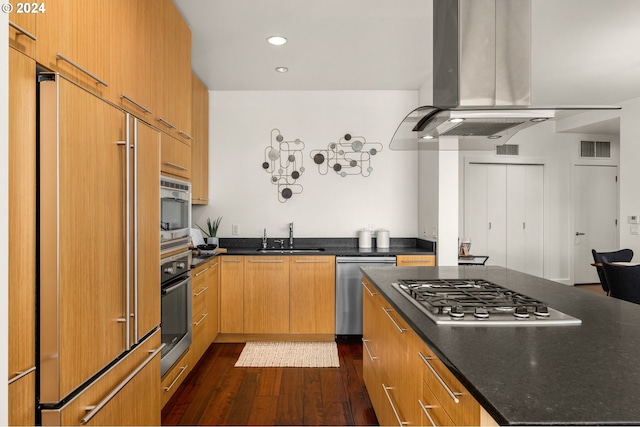 kitchen with dark hardwood / wood-style floors, built in appliances, sink, island range hood, and dark stone countertops