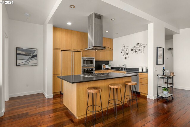 kitchen featuring dark hardwood / wood-style floors, a breakfast bar area, a kitchen island, stainless steel appliances, and extractor fan