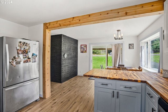 kitchen featuring butcher block countertops, plenty of natural light, stainless steel refrigerator, and light hardwood / wood-style flooring