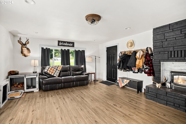 living room with a stone fireplace and light hardwood / wood-style floors