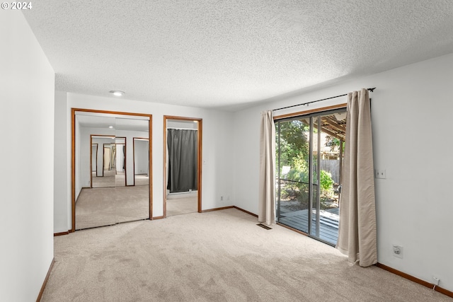 unfurnished room featuring a textured ceiling and light colored carpet