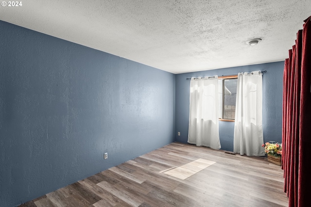 empty room featuring light wood-type flooring and a textured ceiling