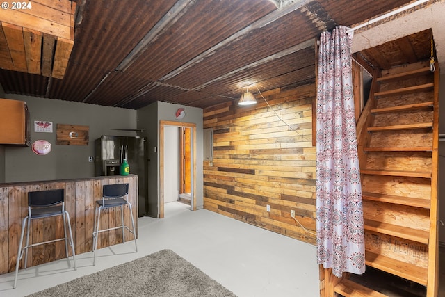 bar featuring wooden walls and black fridge with ice dispenser