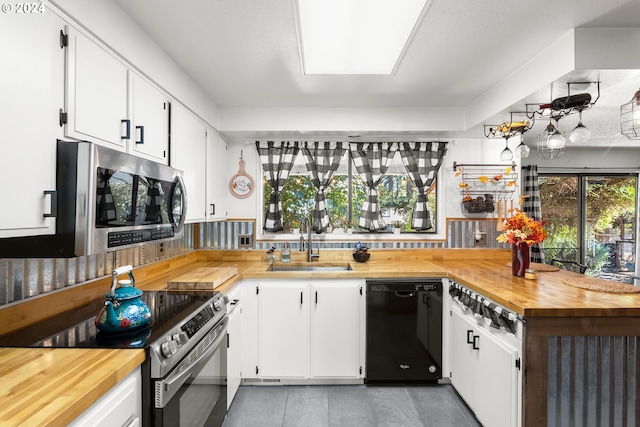 kitchen featuring appliances with stainless steel finishes, white cabinetry, sink, and wood counters