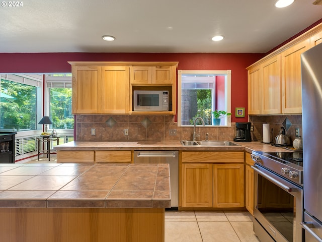 kitchen with sink, stainless steel appliances, a wealth of natural light, and light tile patterned floors