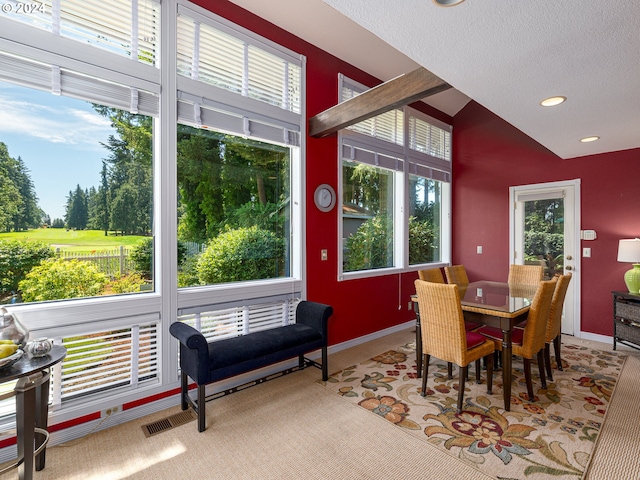 carpeted dining space with lofted ceiling, a textured ceiling, and a wealth of natural light