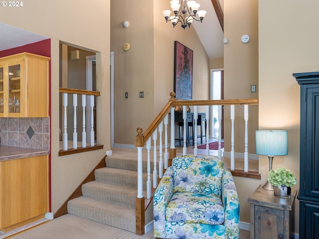 staircase featuring an inviting chandelier and vaulted ceiling