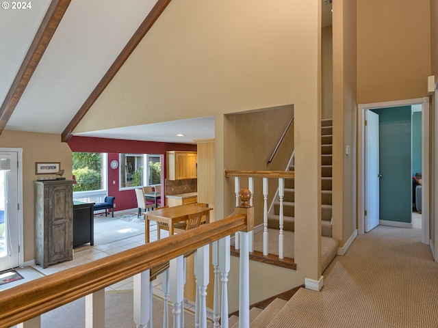 hallway featuring high vaulted ceiling, beam ceiling, and light carpet