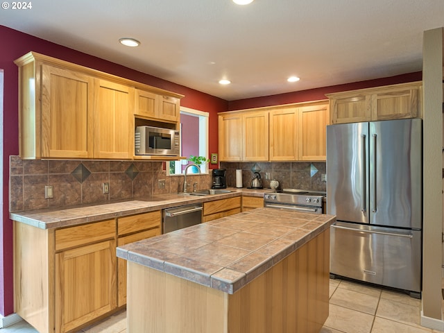 kitchen with stainless steel appliances, a kitchen island, light tile patterned flooring, and sink