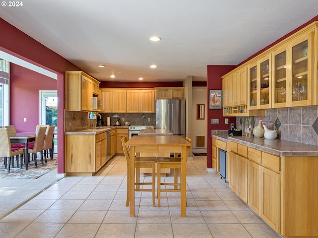 kitchen with sink, stainless steel appliances, light tile patterned flooring, and decorative backsplash