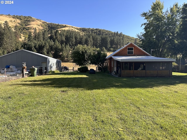 view of yard featuring a sunroom, a mountain view, and an outbuilding