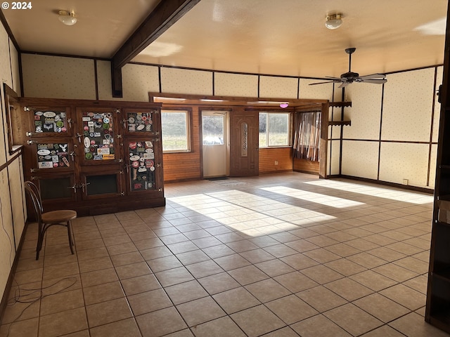 interior space featuring ceiling fan, beamed ceiling, and light tile patterned floors