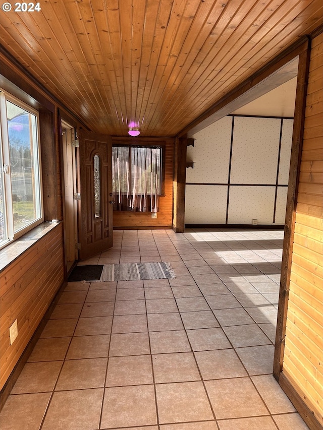 hall with light tile patterned floors, wooden walls, and wood ceiling