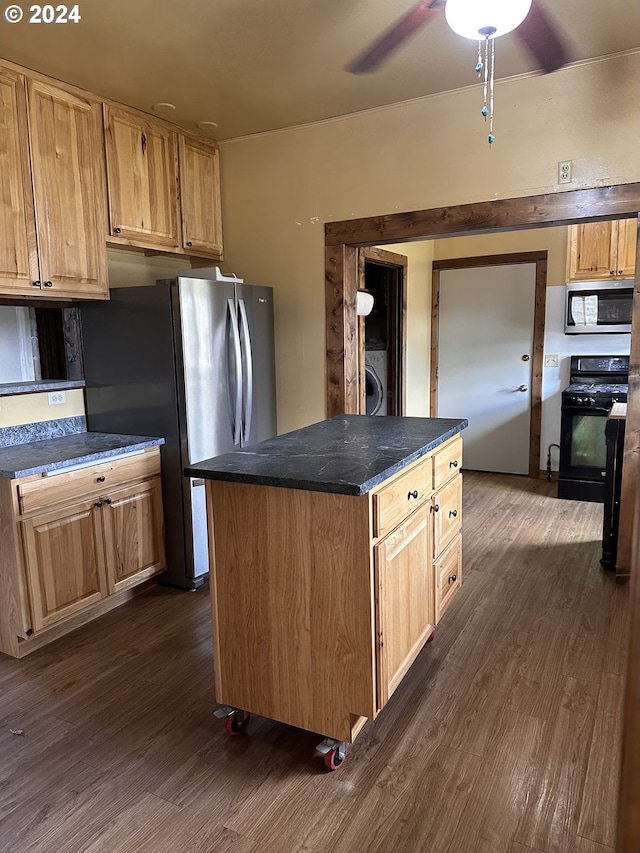 kitchen featuring ceiling fan, a center island, stainless steel appliances, dark hardwood / wood-style floors, and washer / dryer