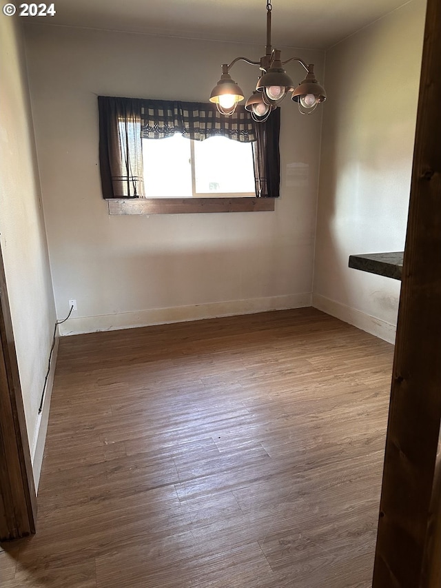 unfurnished dining area featuring hardwood / wood-style floors and an inviting chandelier