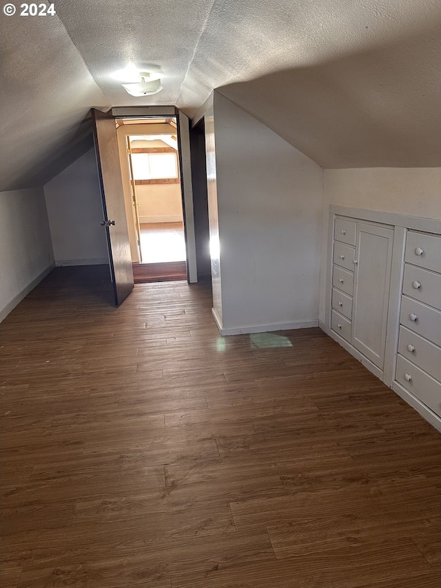 bonus room featuring dark hardwood / wood-style flooring, lofted ceiling, and a textured ceiling