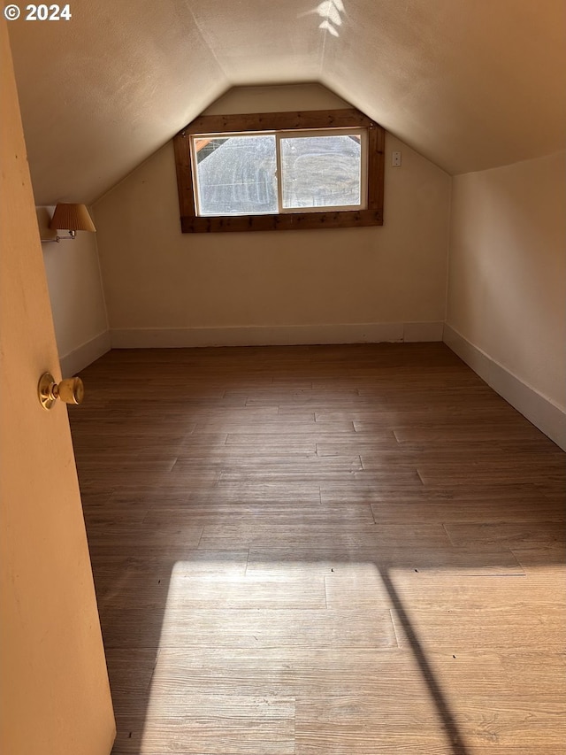 additional living space featuring light hardwood / wood-style floors and lofted ceiling