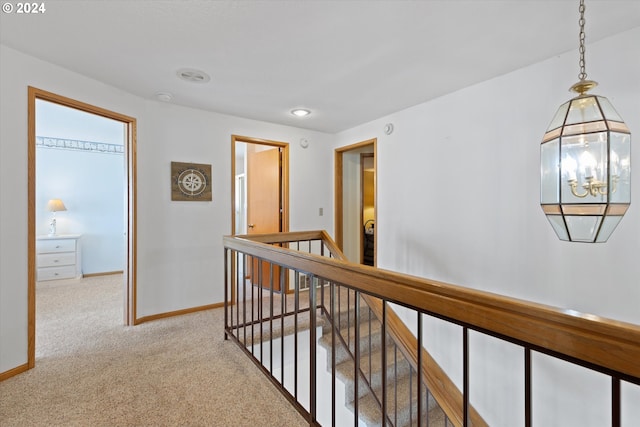 hall featuring light carpet and an inviting chandelier