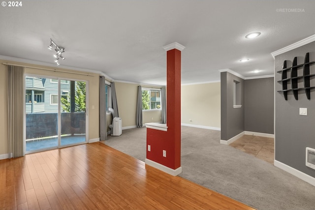 spare room with crown molding, plenty of natural light, and light wood-type flooring