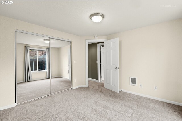 unfurnished bedroom featuring a closet and light colored carpet