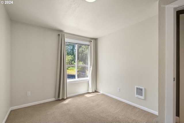 unfurnished room featuring carpet floors, a textured ceiling, and heating unit