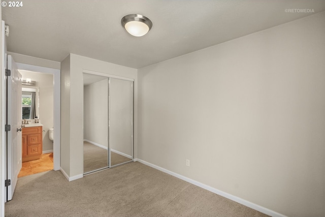 unfurnished bedroom featuring a closet, light colored carpet, and sink