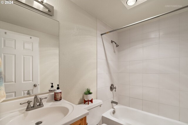 full bathroom with vanity, tiled shower / bath combo, and toilet