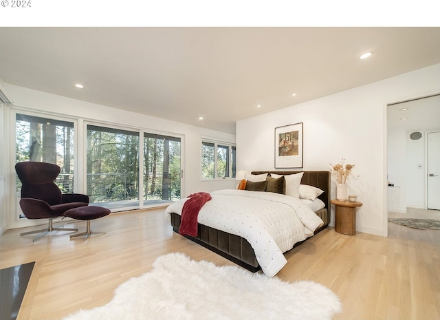 bedroom with ensuite bathroom and light hardwood / wood-style floors