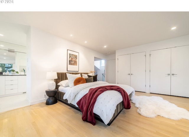 bedroom with multiple closets and light hardwood / wood-style flooring