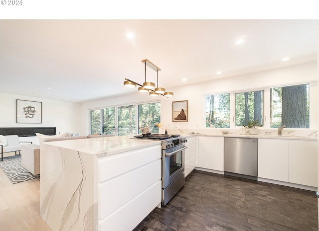 kitchen featuring white cabinetry, light stone counters, kitchen peninsula, pendant lighting, and appliances with stainless steel finishes