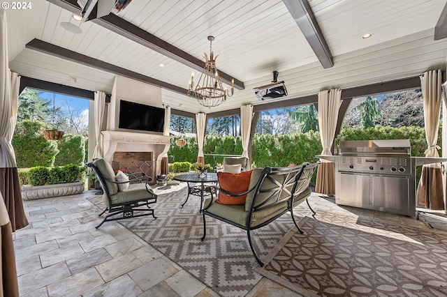 sunroom featuring a wealth of natural light, an inviting chandelier, and an outdoor fireplace