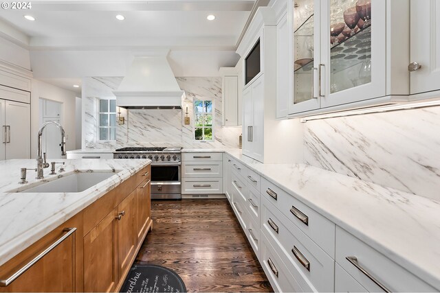 kitchen featuring white cabinets, custom exhaust hood, high end stove, sink, and dark wood-type flooring