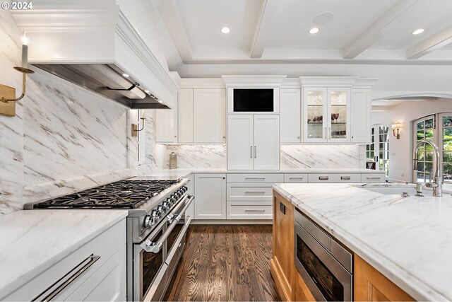 kitchen featuring white cabinets, appliances with stainless steel finishes, decorative backsplash, and premium range hood