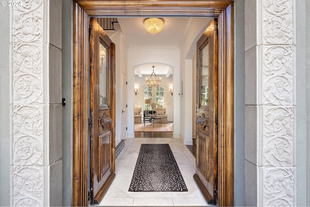 hallway with a notable chandelier, light tile patterned floors, and crown molding