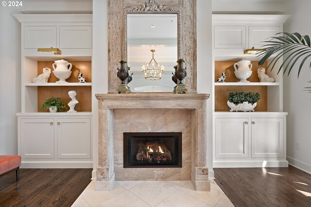 room details featuring a fireplace, built in features, hardwood / wood-style flooring, and an inviting chandelier