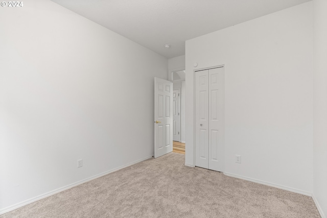 unfurnished bedroom featuring light colored carpet and a closet