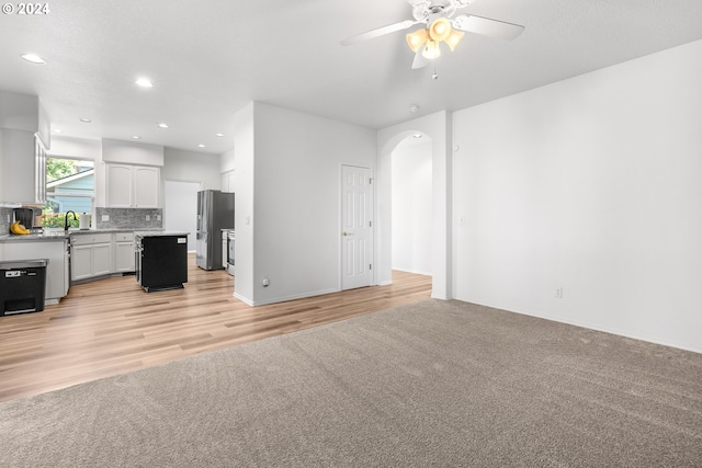 unfurnished living room featuring ceiling fan and light wood-type flooring