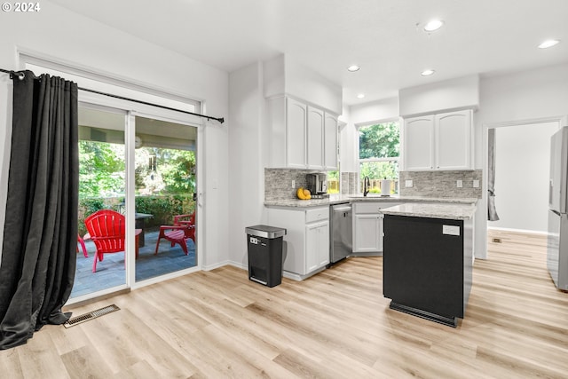 kitchen with a healthy amount of sunlight, backsplash, white cabinetry, and stainless steel appliances