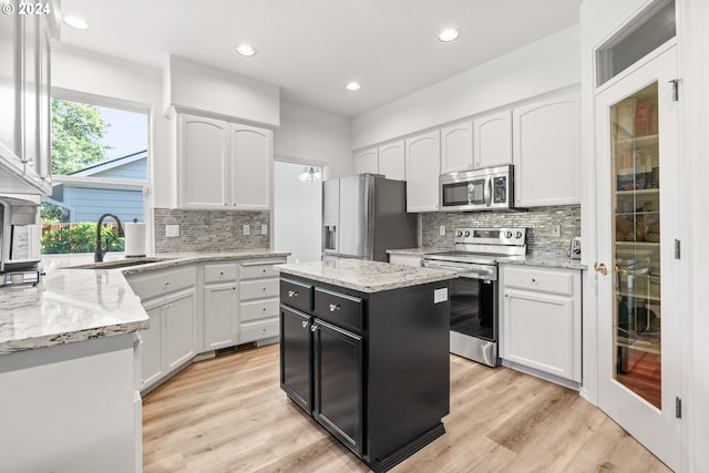 kitchen featuring white cabinetry, sink, a center island, appliances with stainless steel finishes, and light wood-type flooring