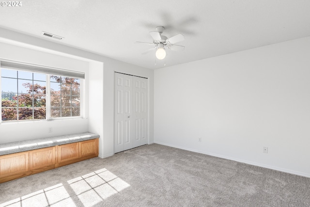 unfurnished bedroom featuring ceiling fan, light carpet, and a closet