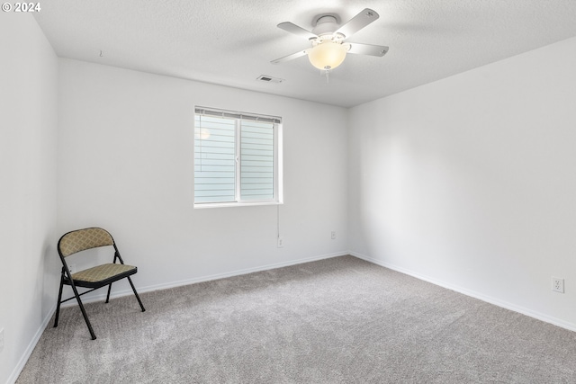 carpeted spare room featuring a textured ceiling and ceiling fan